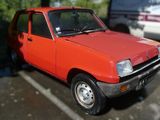 une voiture orange garée sur un parking à côté d'une camionnette