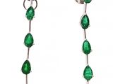 une paire de boucles d'oreilles avec des pierres vertes sur fond blanc