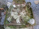 une statue recouverte de mousse, posée par terre au milieu de la rue