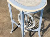 une petite table avec un plateau en marbre posée sur un sol en béton