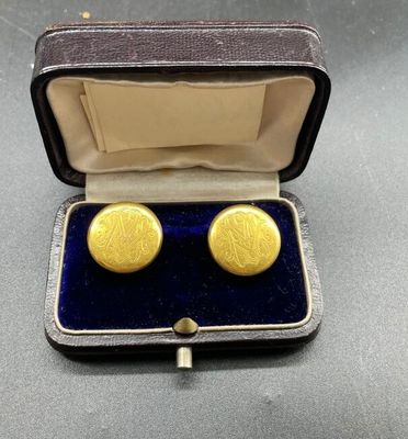 une photo d'une paire de boutons de manchette en or dans un étui