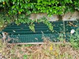 a bench that is sitting in the grass by the wall