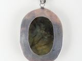 a close up of a silver pendant with a green stone in it