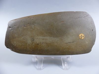 un gros rocher posé sur un socle, sur une surface blanche