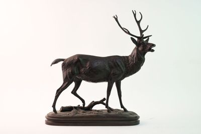 statue d'un cerf debout sur un socle en bois, sur fond blanc