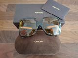 Lunettes de soleil Tommy Ford avec leur boîte et leur étui, posées sur un parquet