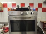 a stainless steel oven in a kitchen with red and white checkered walls