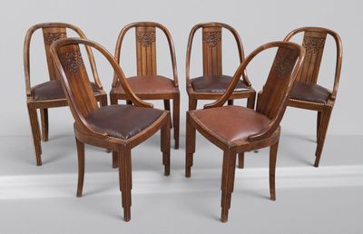 quatre chaises en bois avec des assises recouvertes de cuir et un mur blanc