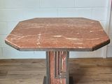 a small table with a red marble top on a wooden floor