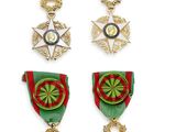quatre médailles et une croix sont exposées sur un fond blanc