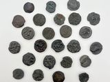 Plusieurs pièces de monnaie romaines antiques sont disposées en cercle sur une surface blanche.