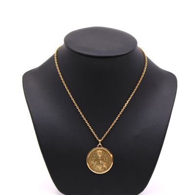un collier en or avec une pièce de monnaie sur le cou d'un mannequin