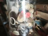a jar with buttons in it sitting on a shelf