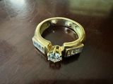 une bague en or sertie d'un diamant, posée sur une table