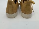 a pair of tan sneakers with white soles on a white surface