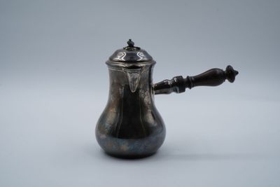 une cafetière ancienne en argent avec une poignée en bois sur fond blanc