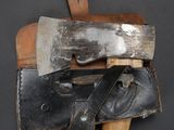 a close up of an old axe and a leather sheath on a black background
