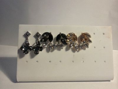 five pairs of earrings sitting on a white display board
