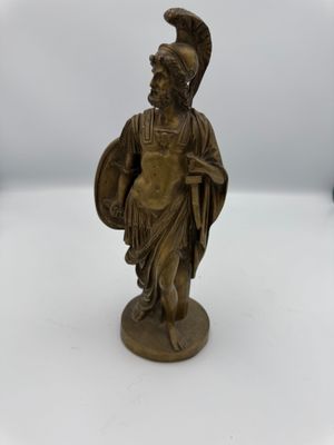 an old bronze statue of a roman soldier holding a shield and shield