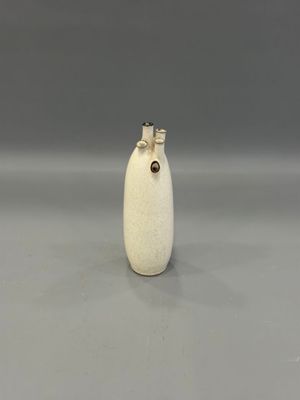 un petit vase blanc surmonté d'une fleur