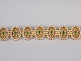 un bracelet en or orné de pierres vertes et de perles