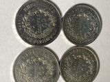 four different british coins sitting on top of a white surface