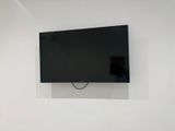 une télévision à écran plat fixée au mur au-dessus d'un lit