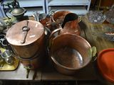 many copper pots and pans on a table