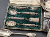 a box of silver spoons and other silverware on a table