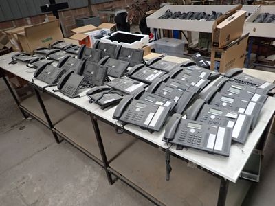 a lot of telephones sitting on a table in a warehouse