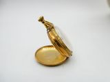 a gold pocket watch sitting on a white surface