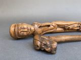 an old wooden walking stick with a carved figure on it
