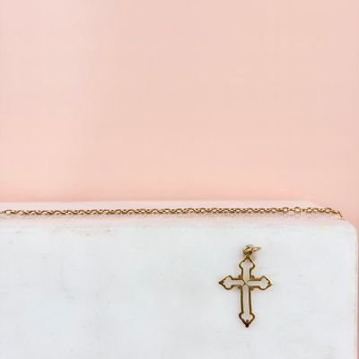 une pochette blanche ornée d'une croix dorée sur le devant