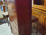 a tall wooden cabinet with drawers in a room