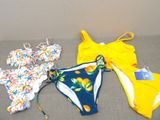plusieurs maillots de bain étalés sur un canapé dans une pièce