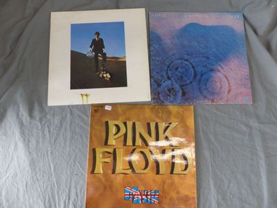 two pink floyd albums on a bed with a blue blanket