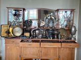 une grande armoire en bois sur laquelle sont disposés de nombreux objets en argent