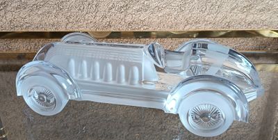 une maquette argentée d'une voiture exposée sur une table en verre