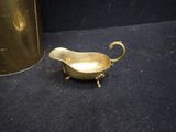 a small brass gravy on the floor next to a vase