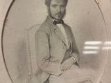 portrait of a man in a suit and bow tie sitting in a chair