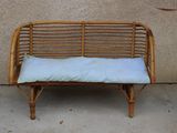 un banc en osier sur lequel est posé un coussin blanc