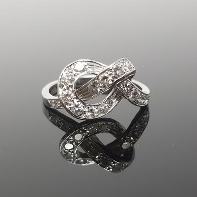 une photo d'une bague sertie de diamants posée sur une surface réfléchissante