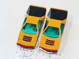 two toy cars sitting on top of a piece of paper