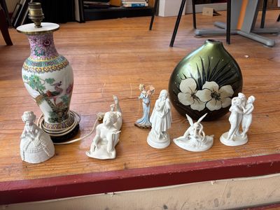 de nombreuses figurines posées sur une table, avec un vase en arrière-plan