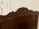 carvings on the headboard of a wooden bed frame in a bedroom