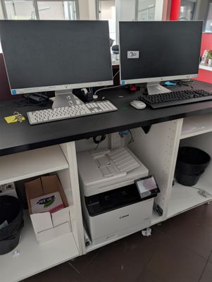 two computer monitors and a printer sitting on a desk