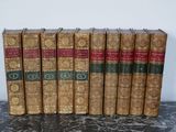 several old books are lined up on a table in front of a white wall
