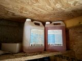 two jugs of liquid sitting on a shelf in a room