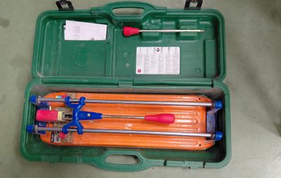 une mallette verte posée par terre, contenant des outils