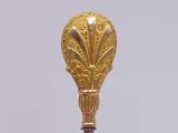 a gold spoon with a red handle on a white table